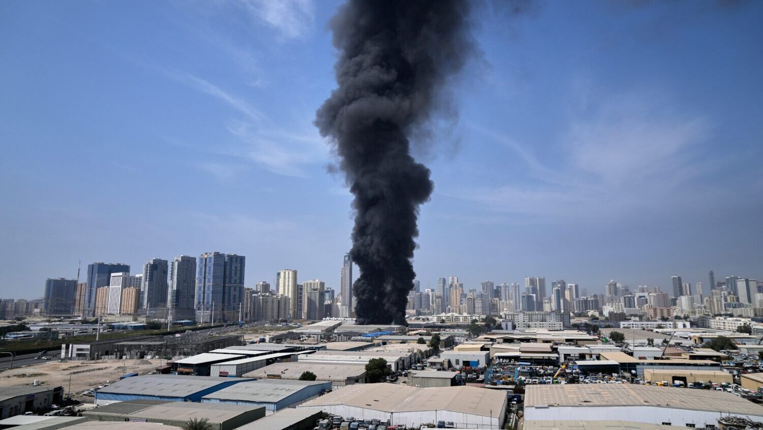 A black plume of smoke rises from a warehouse at the industrial area of Sharjah City in the United ...