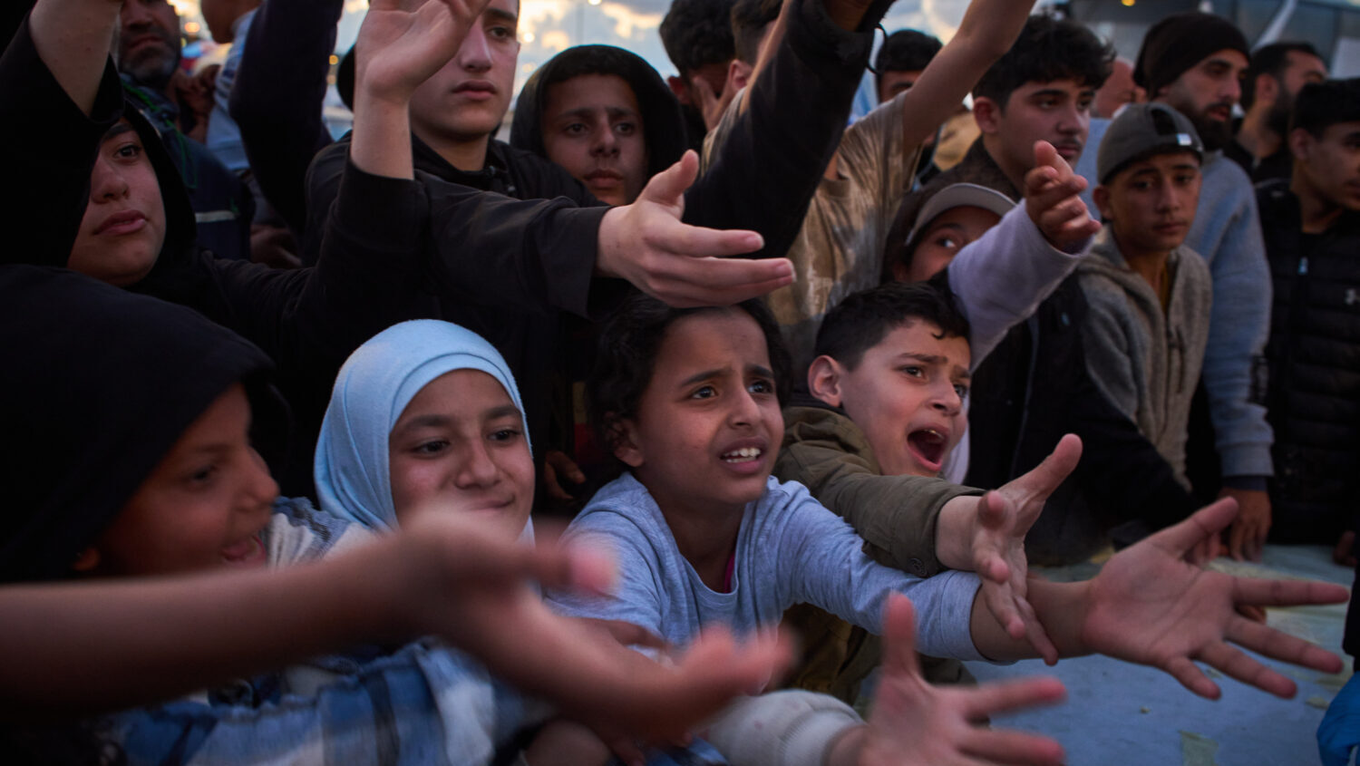 Displaced people wait to receive donated food beside the tents they use as shelters after fleeing I...