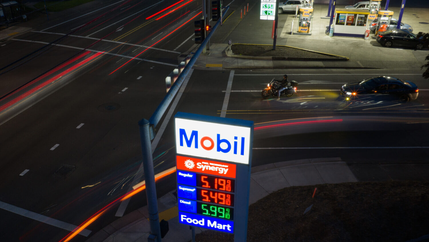 In this photo taken with a slow shutter speed, traffic moves past a sign for a Mobil gas station on...