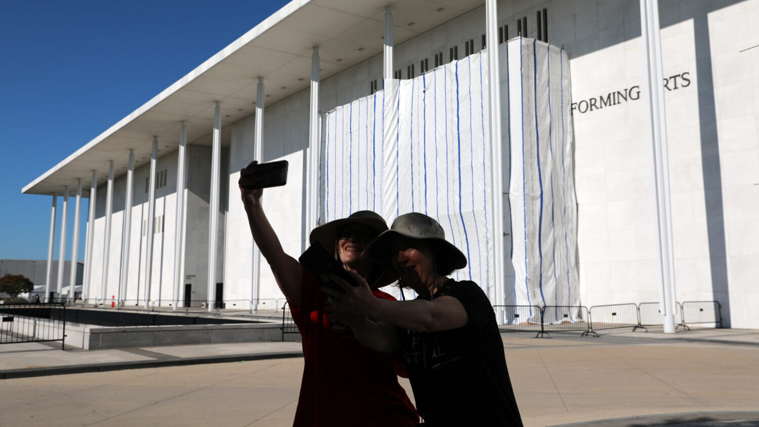 Women take a selfie as the wall of the John F. Kennedy Center for the Performing Arts is covered in...
